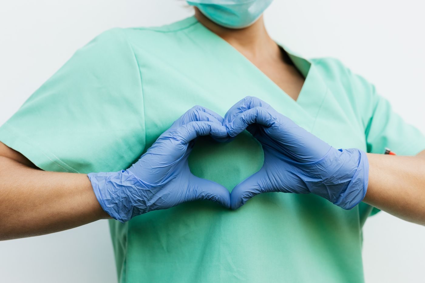 Profissional de saúde com luvas formando um coração com as mãos
